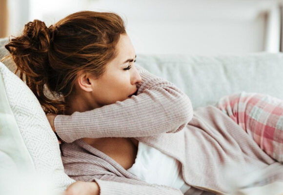 young-woman-coughing-into-elbow-while-lying-down