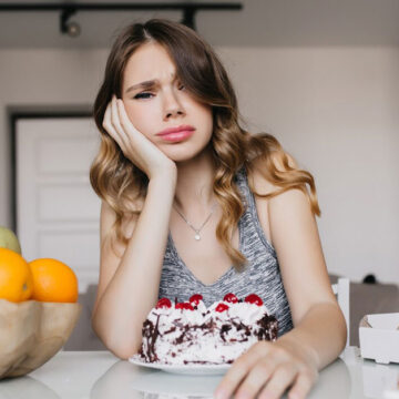 bored-young-lady-sitting-table-with-cake-fruits-pretty-white-girl-posing-during-breakfast_197531-9715