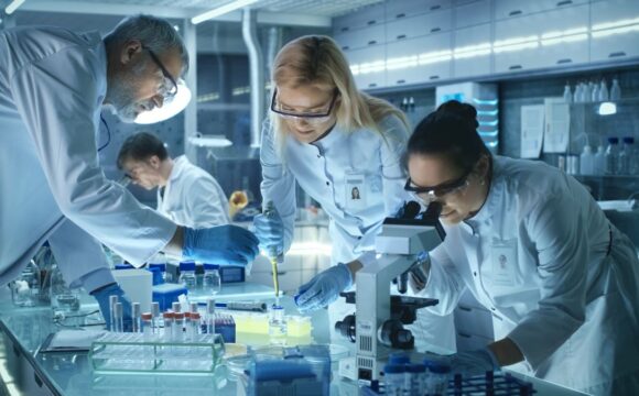 Team of Medical Research Scientists Work on a New Generation Disease Cure. They use Microscope, Test Tubes, Micropipette and Writing Down Analysis Results. Laboratory Looks Busy, Bright and Modern.