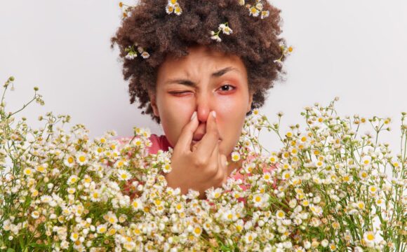 woman-has-problems-with-breathing-holds-nose-suffers-from-allergy-camomile-holds-big-bouquet-flowers-has-red-itchy-eyes