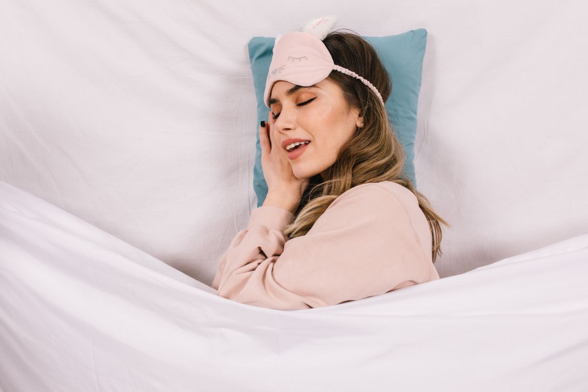 Debonair young woman sleeping in bed. Overhead portrait of dreamy girl lying on pillow.