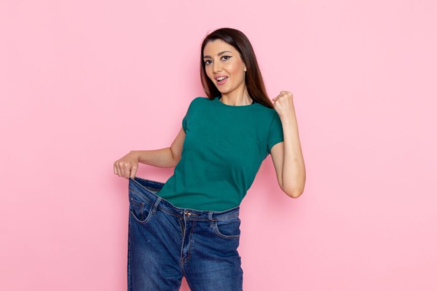 front-view-young-female-green-t-shirt-checking-her-waist-light-pink-wall-waist-sport-exercise-workouts-beauty-slim-athlete-female